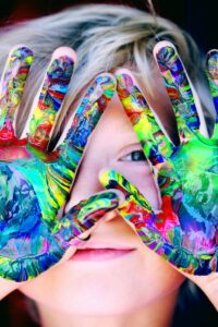 Vibrant close-up of a child's hands covered in colorful paint, expressing creativity and fun.