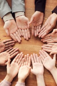 Top view of diverse hands forming a circle on a wooden table, symbolizing unity and diversity.
